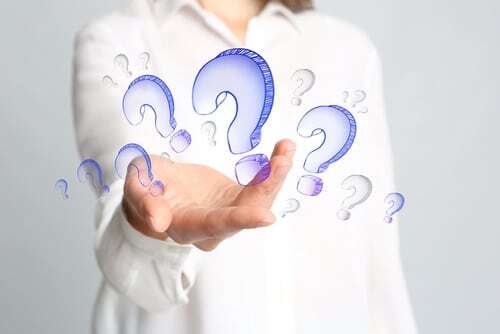 Person holding hand up with blue question marks floating around, symbolizing dental care questions.