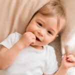 Toddler with hand in mouth demonstrating why using teeth as tools is harmful.