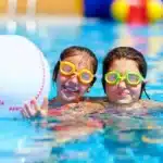 Two children enjoying swimming with colorful goggles, demonstrating active hobbies compatible with orthodontic care.
