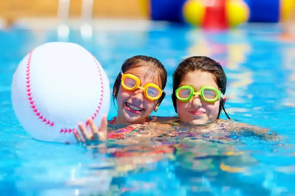 Two children enjoying swimming with colorful goggles, demonstrating active hobbies compatible with orthodontic care.