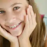 Happy teenager with metal braces smiling at dental practice in Spring, TX.