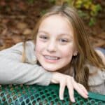 Young girl with colorful holiday braces smiling outdoors in Spring, TX.