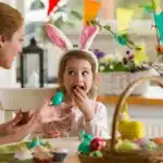 Mother and child with bunny ears enjoying Easter candy together at home.