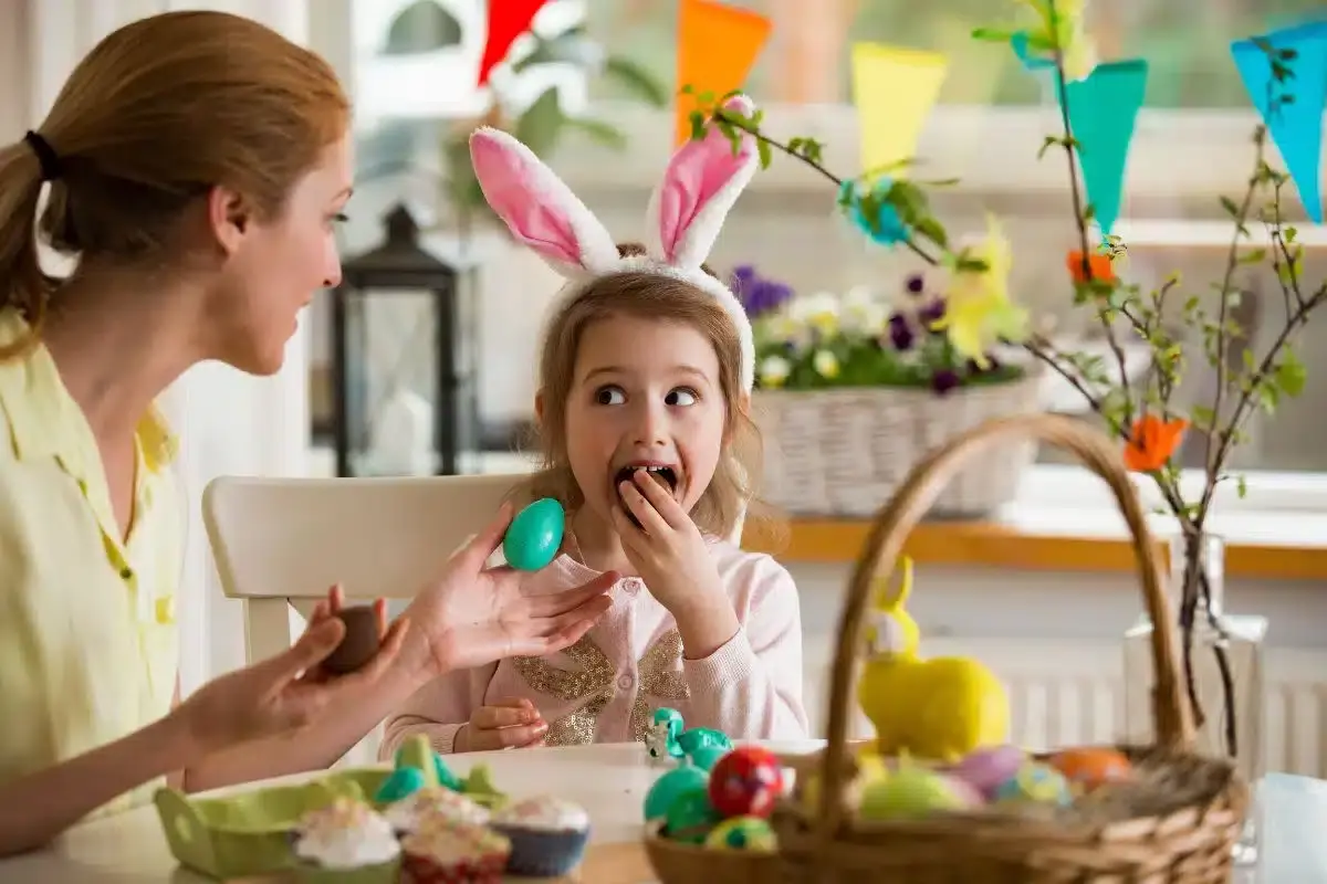 Mother and child with bunny ears enjoying Easter candy together at home.