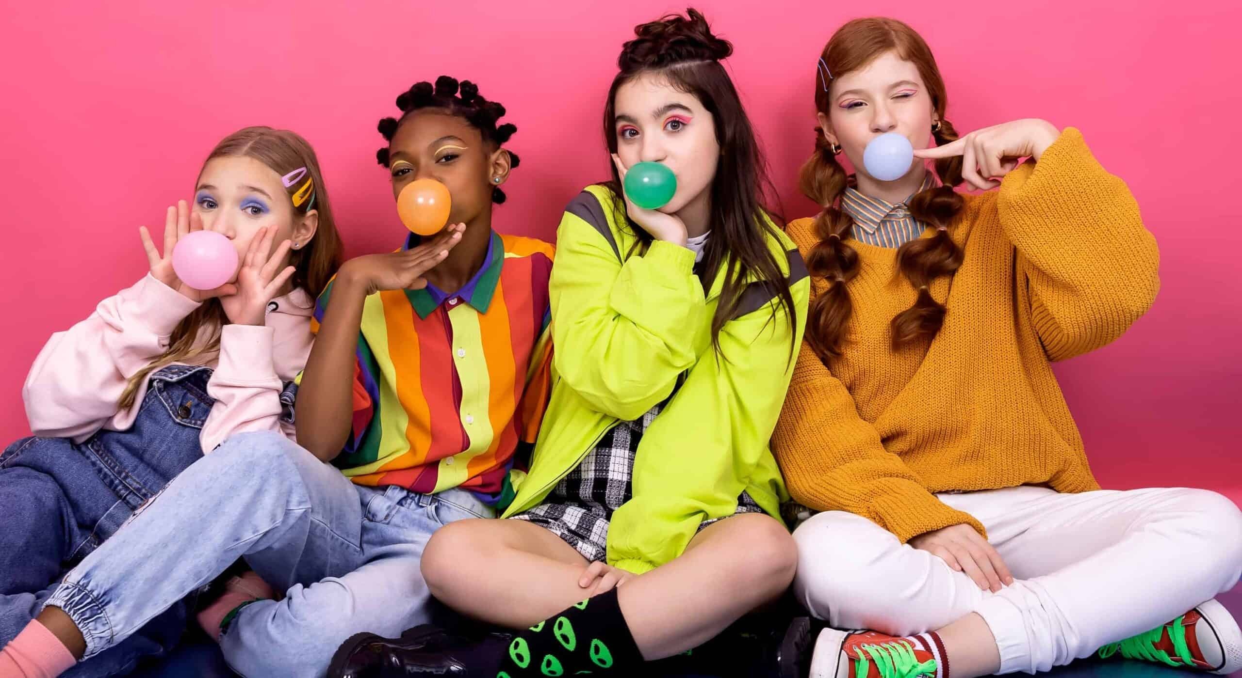 Four young people blowing colorful bubbles against pink background, promoting xylitol sugar alternative.