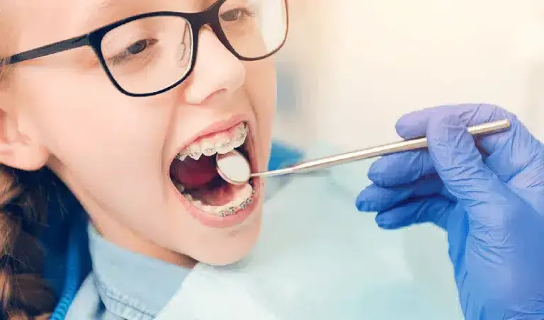 Young patient receiving dental examination with orthodontic braces during early orthodontic care evaluation.