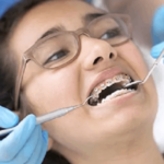 Patient receiving orthodontic examination with braces visible during dental consultation.