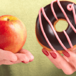 Hand holding a red apple next to a chocolate donut, illustrating healthy versus sugary food choices for children's dental he.