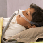 Man sleeping with CPAP mask for sleep apnea treatment.