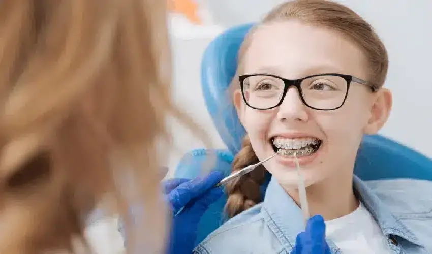 Young patient with braces and glasses smiling during dental examination in Spring, TX.
