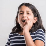 Young girl with hand near mouth experiencing tooth sensitivity or dental discomfort.