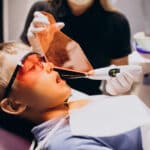 Young patient receiving laser dental treatment with protective eyewear during pediatric dentistry procedure.