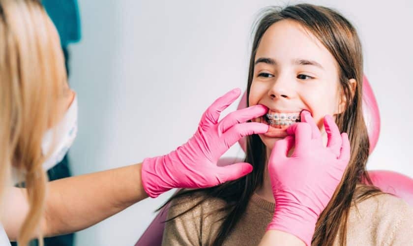 Orthodontist fitting clear aligners on young patient's teeth during Spring dental treatment.