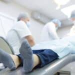 Patient relaxing in dental chair during sedation dentistry procedure with dental team.