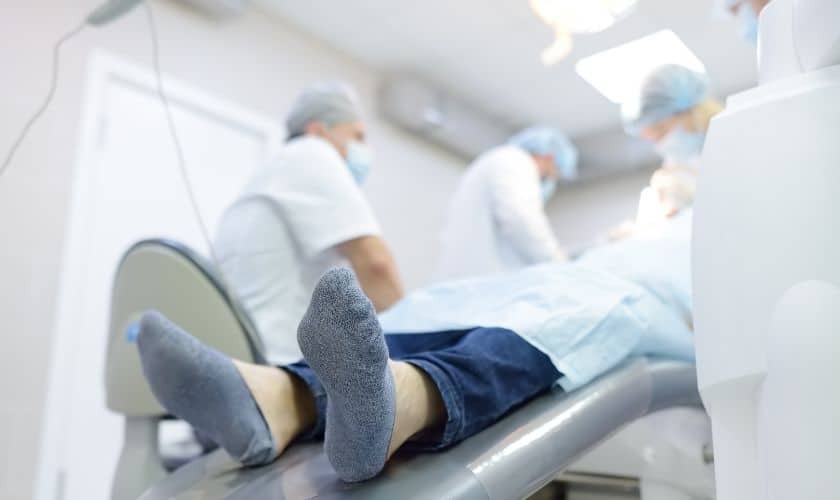 Patient relaxing in dental chair during sedation dentistry procedure with dental team.
