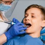 Pediatric dentist treating young patient's teeth with dental laser in Spring, TX.