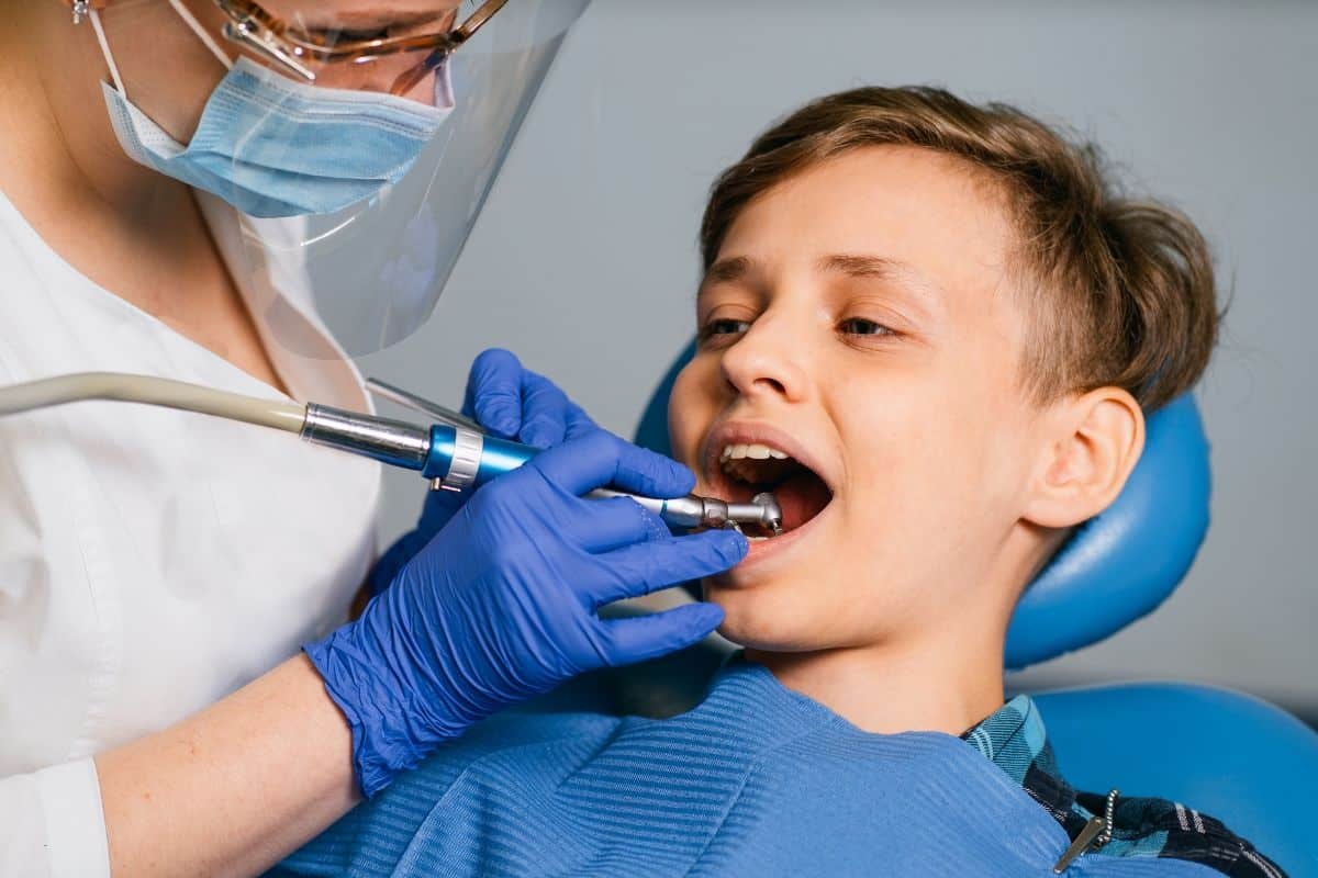 Pediatric dentist treating young patient's teeth with dental laser in Spring, TX.
