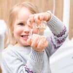 Happy child rinsing mouth after pediatric dental treatment in Spring, TX.