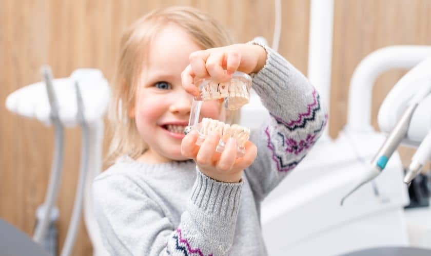Happy child rinsing mouth after pediatric dental treatment in Spring, TX.