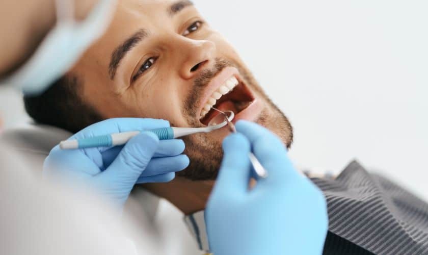 Dentist examining patient's teeth during dental checkup with dental tools.