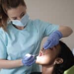 Pediatric dentist examining a child patient's teeth during a dental visit in Spring, TX.