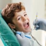 Young boy smiling with mouth open during dental examination at Spring pediatric dental office.