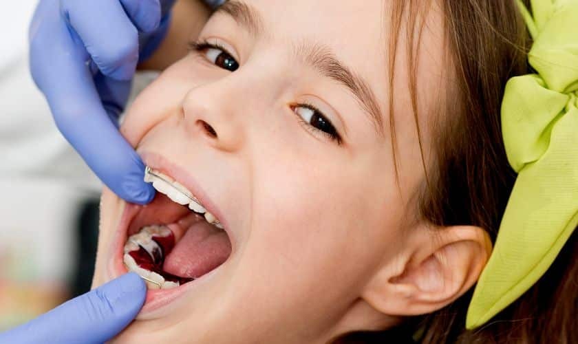 Young patient receiving dental examination with orthodontist checking teeth during consultation.