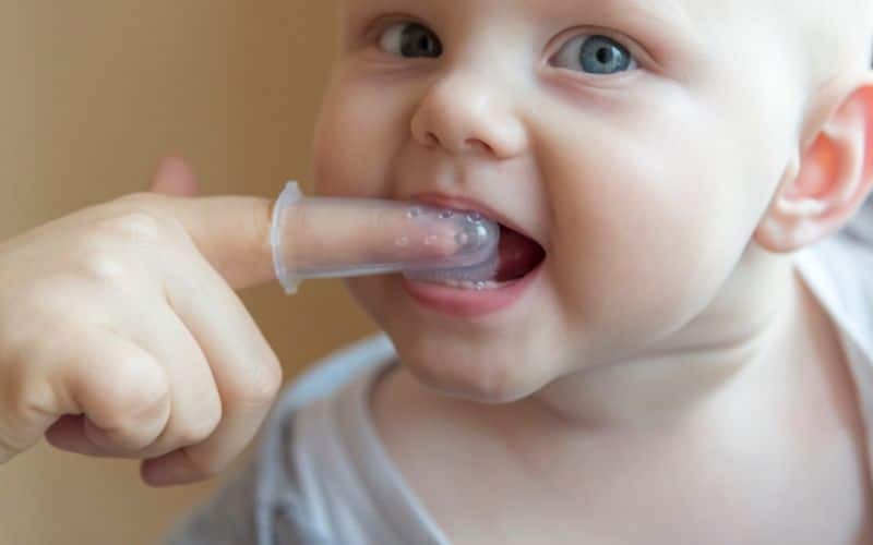 Happy toddler using a teething toy to soothe sore gums during the teething phase.