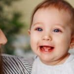 Happy baby with teething smile showing first teeth during developmental stage.