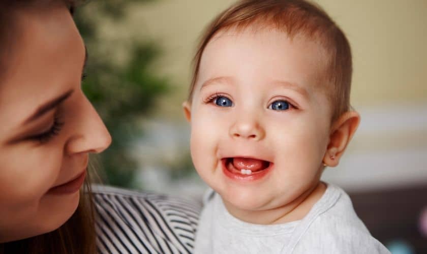 Happy baby with teething smile showing first teeth during developmental stage.