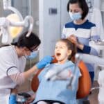 Pediatric dentist examining young patient's teeth during dental checkup in Spring office.