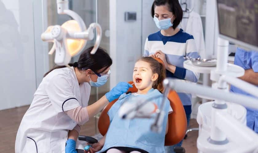 Pediatric dentist examining young patient's teeth during dental checkup in Spring office.