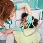 Pediatric dentist examining young patient's teeth during dental checkup at Spring, TX practice.