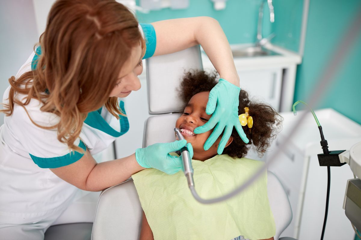 Pediatric dentist examining young patient's teeth during dental checkup at Spring, TX practice.