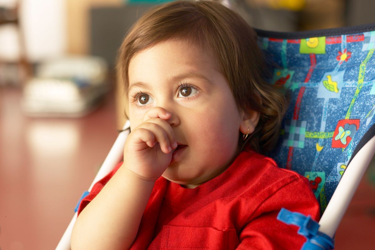 Young child in red shirt sitting in dental chair with colorful patterned headrest during pediatric dental visit.