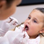 Young patient receiving dental examination with mirror and explorer during checkup.