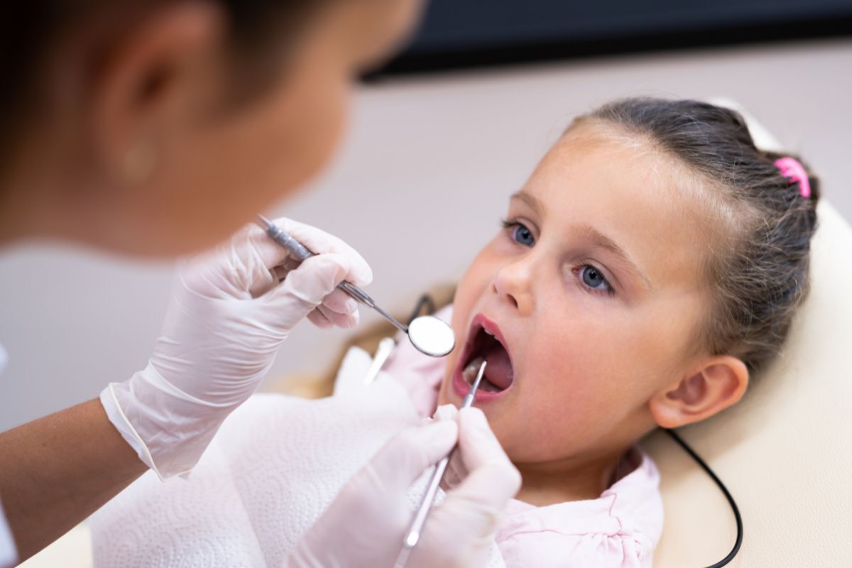 Young patient receiving dental examination with mirror and explorer during checkup.