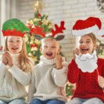 Happy children wearing festive Christmas hats and props smile together during holiday break.