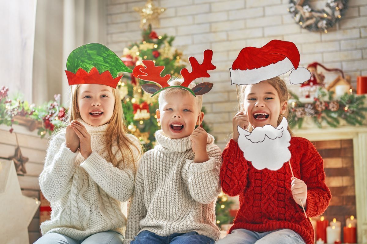 Happy children wearing festive Christmas hats and props smile together during holiday break.