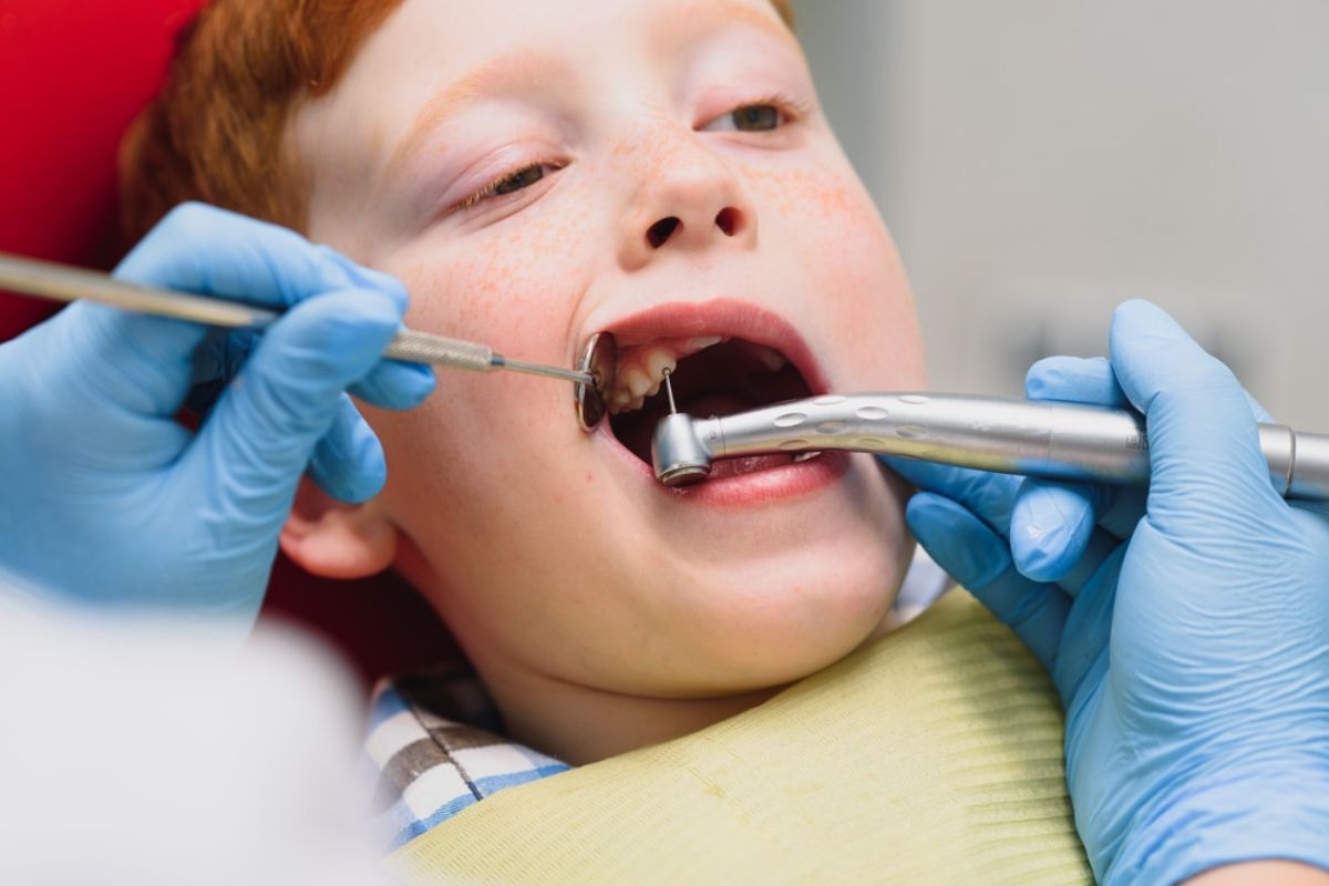 Young patient receiving dental examination with mirror and explorer tool during checkup.