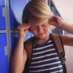 Child experiencing headache pain near temple, relating to TMJ disorder symptoms.