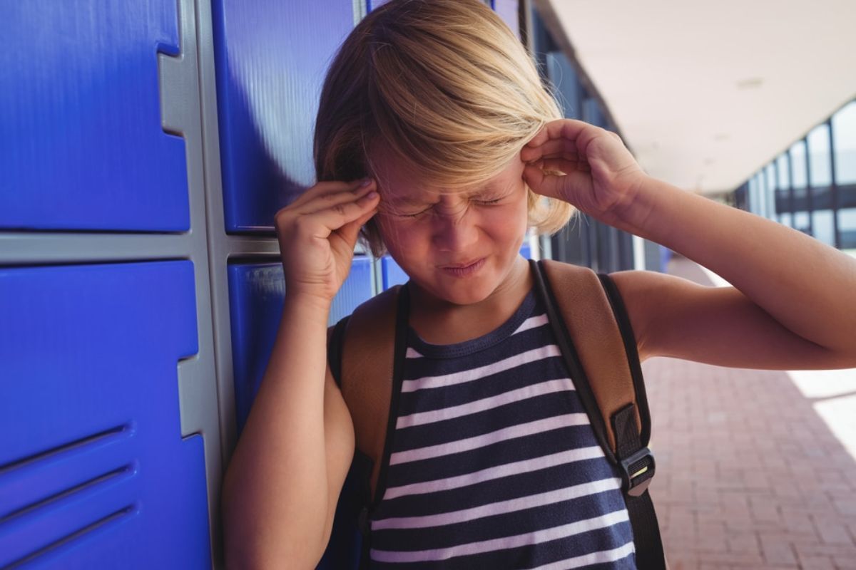 Child experiencing headache pain near temple, relating to TMJ disorder symptoms.
