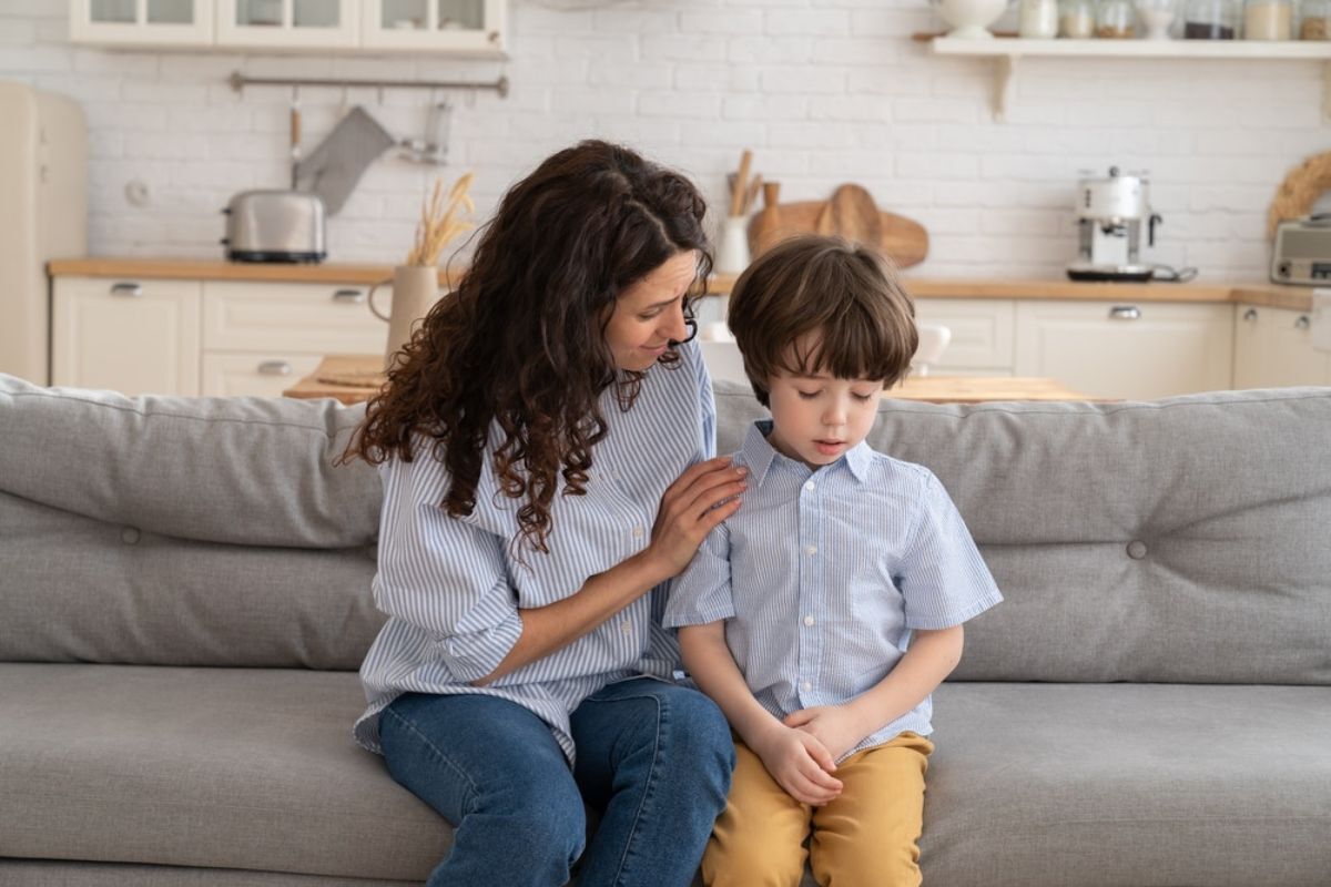 Mother talking with young boy about dental health on couch at home.