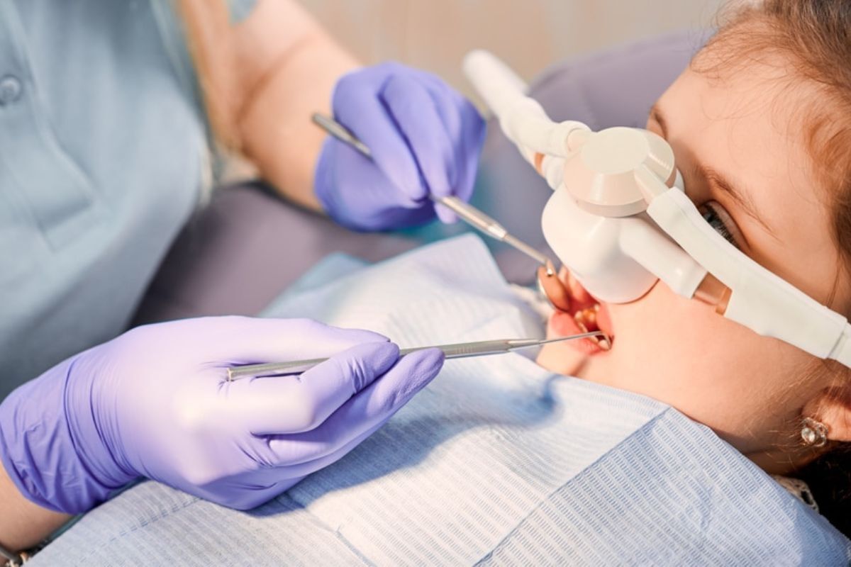 Pediatric dentist examining child's teeth with intraoral camera during sedation dentistry consultation in Spring, TX.