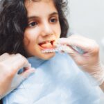 Child receiving Invisalign aligner placement during orthodontic treatment at dental office.