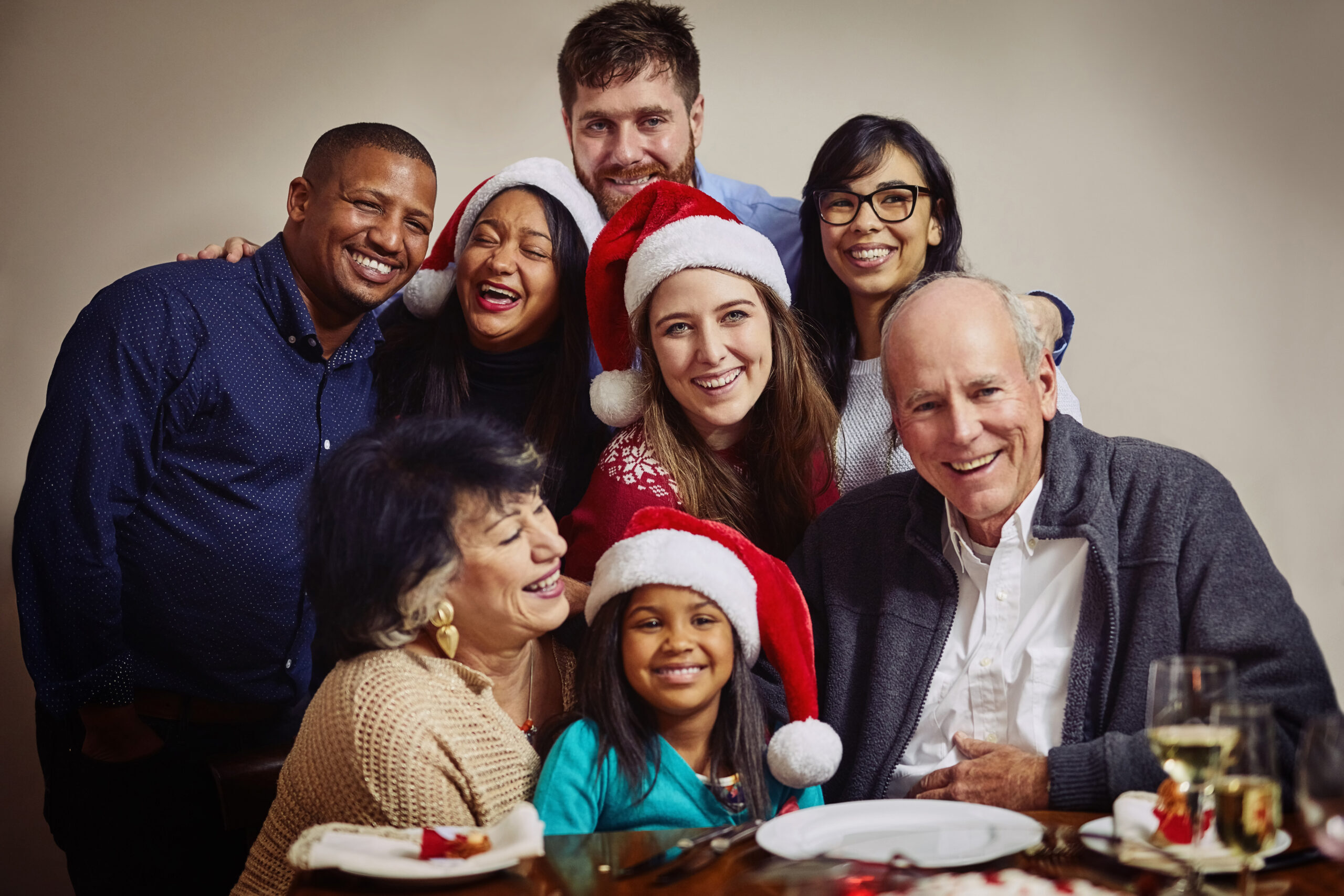 Happy multi-generational family celebrating Christmas together with Santa hats and festive meal.