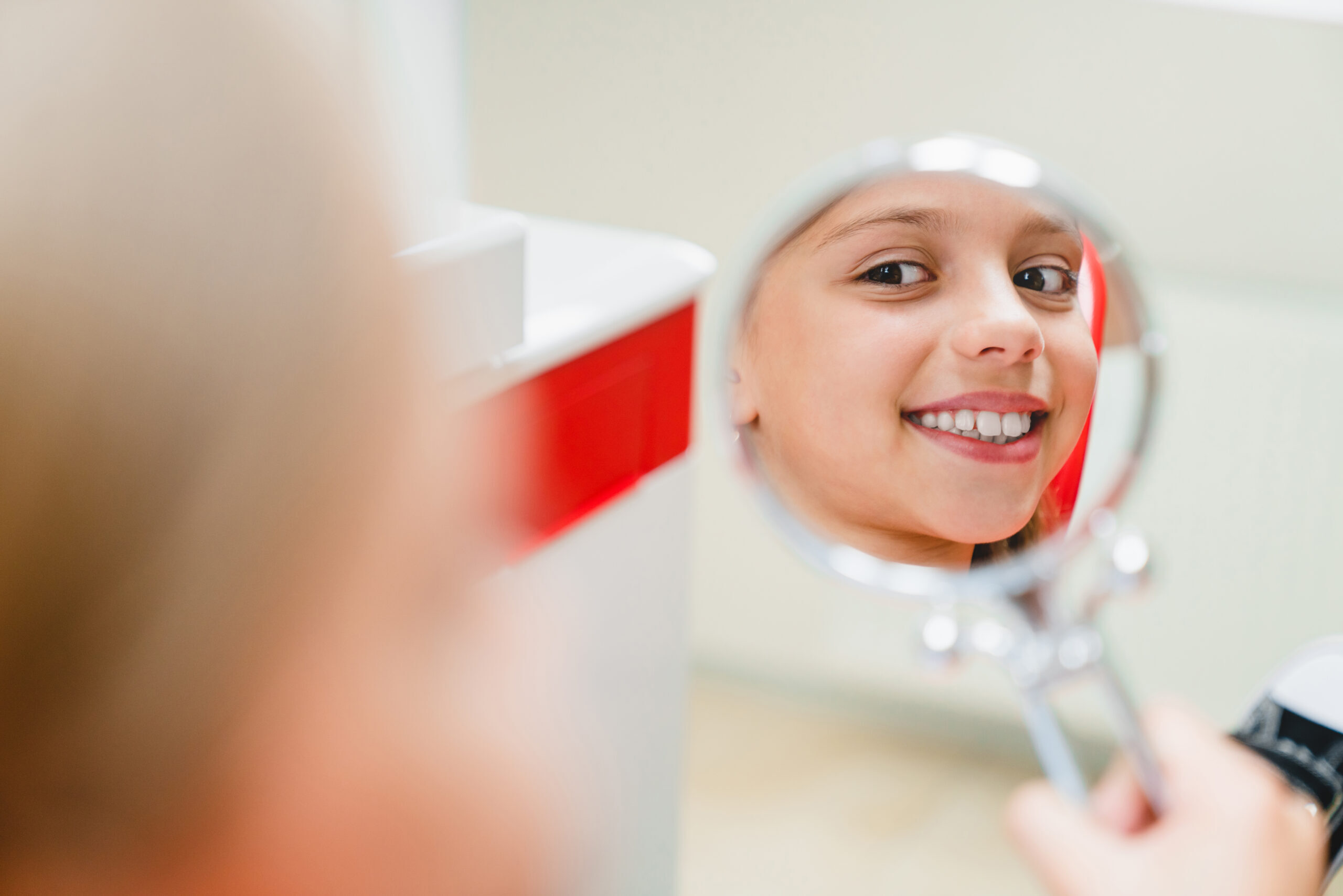 Child smiling at dental mirror during orthodontic treatment in Spring, TX.