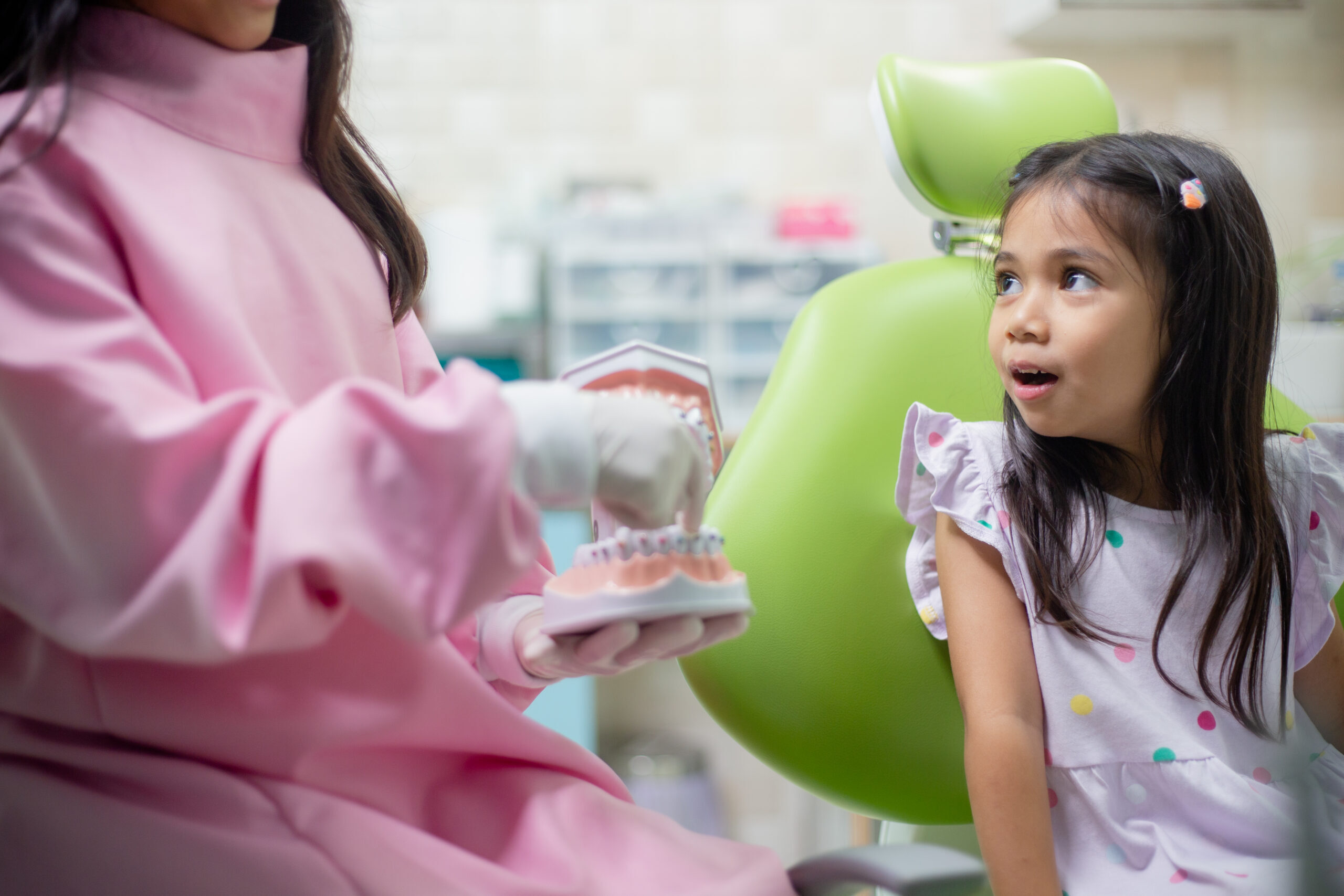 Young patient in dental chair smiles as dentist explains orthodontic treatment during consultation.