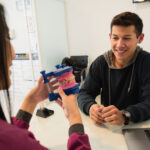 Young teen patient examining dental model with orthodontist during consultation.