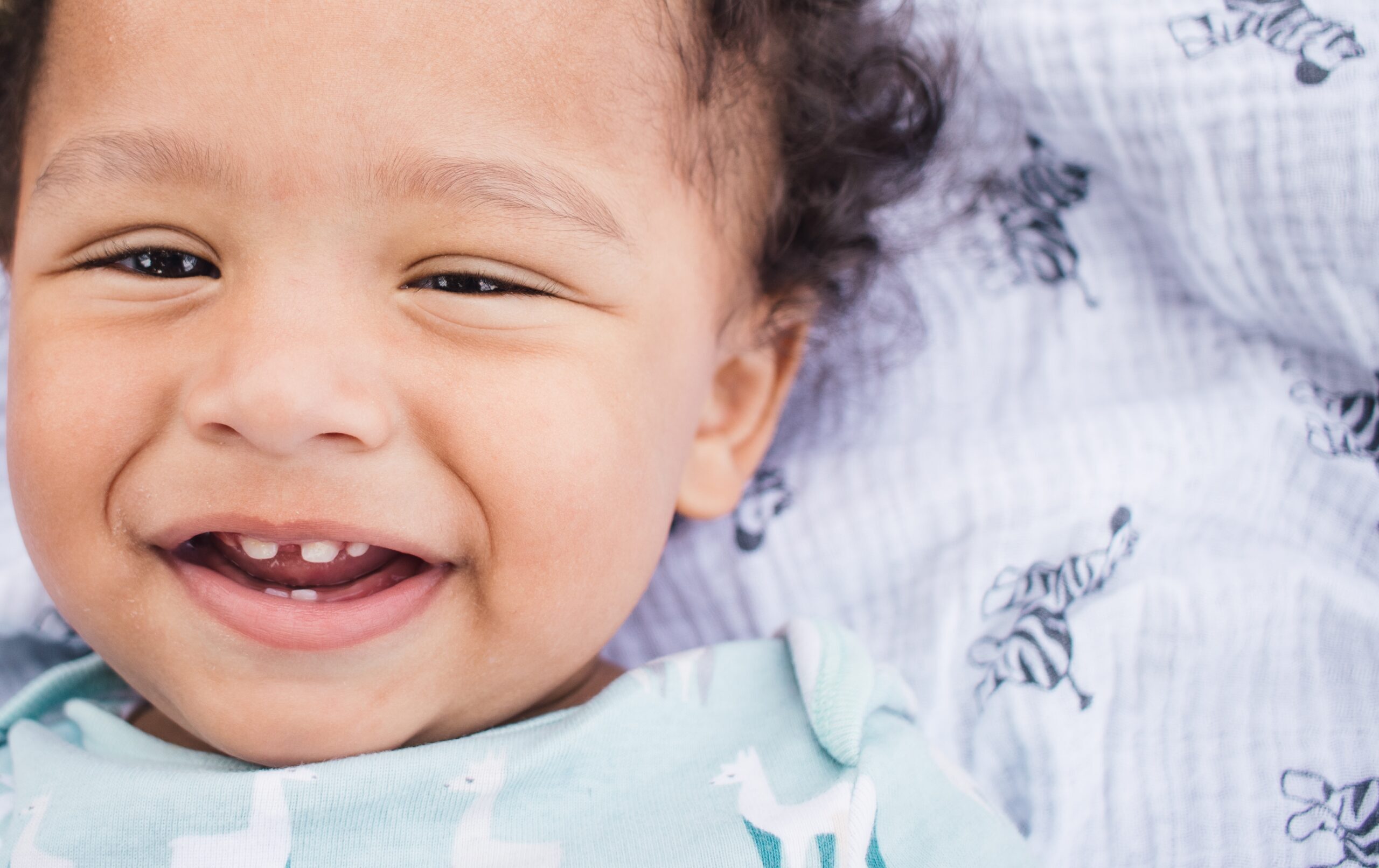 Happy toddler smiling, showing primary teeth during early childhood development.